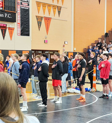 Line of students pledging allegiance to the USA flag in the gym