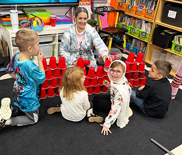 Teacher sitting on the classroom floor with a group of students