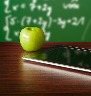A green apple next to a tablet