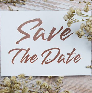 A card with the words Save The Date and small flowers around it