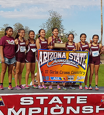 Girls cross country team holding Arizona State championship banner