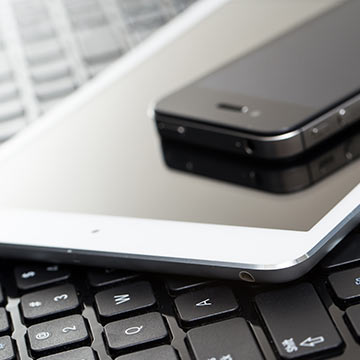A cell phone and tablet on top of a laptop