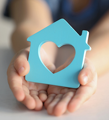 Little hands holding a blue wood house