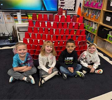 four students with a cup tower