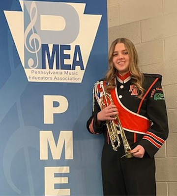 Student with her horn beside a PMEA sign