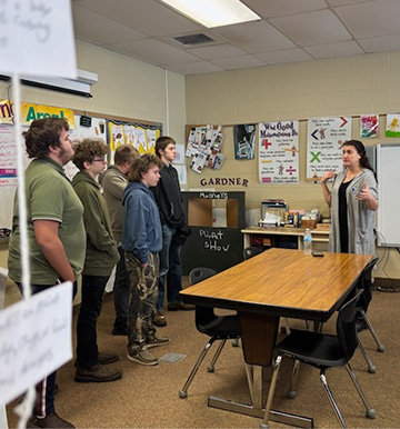 Students in a classroom listening to an adult