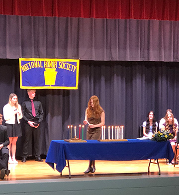 Student lighting candles during a National Honor Society celebration