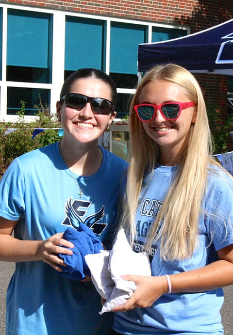 two girls smiling at the camera putside on a sunny day
