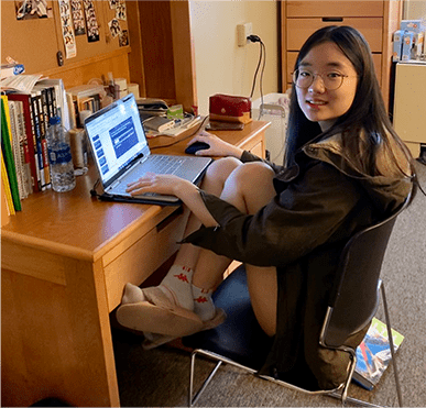 Girl sitting in her dorm working on a laptop