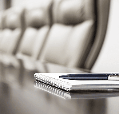 Chairs at a table with a notebook and pen on top