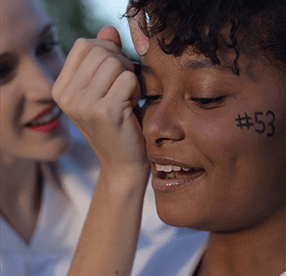 girl painting another girl's face for team spirit