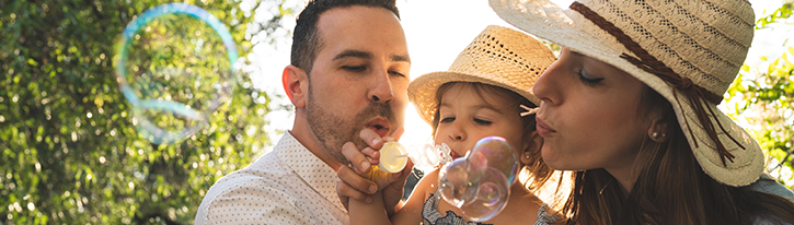 parents with toddler blowing bubbles