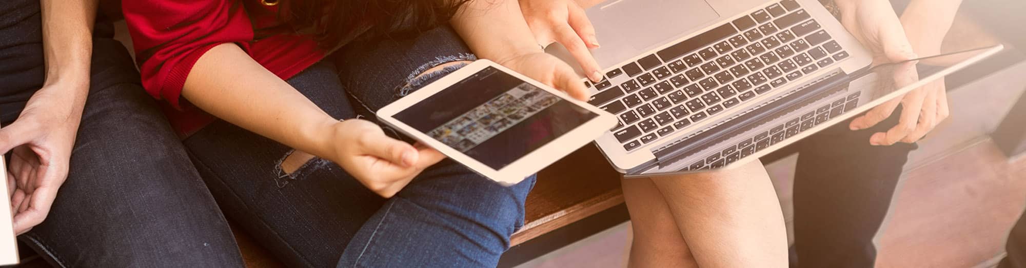 High school students sitting outside and helping each other with online assignments