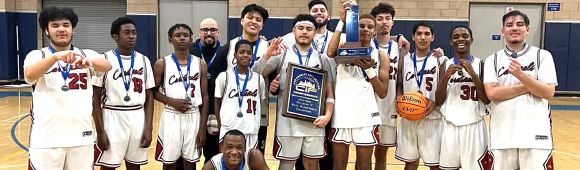 Boys basketball team wearing blue ribbons and holding trophy