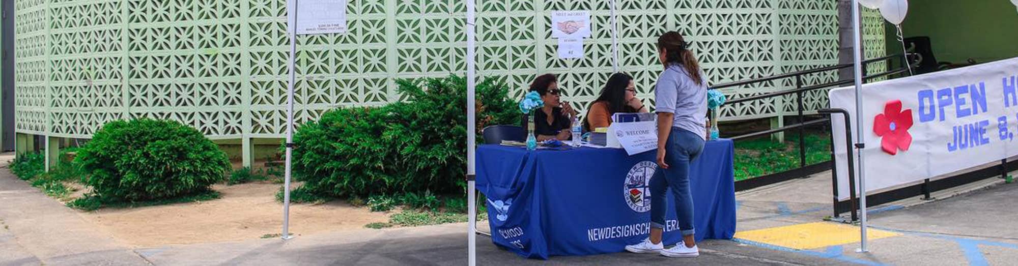 A student talking to two adults at an outdoor display table