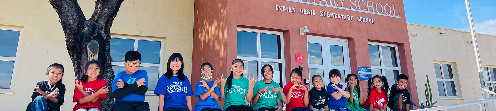 Students sitting in front of the Indian Oasis Elementary school building