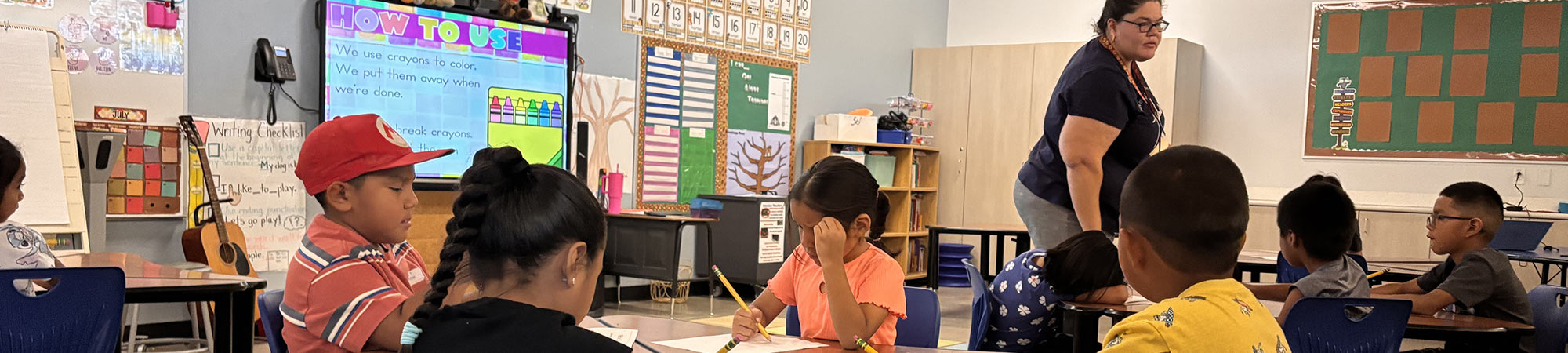 Students doing work in class with the teacher helping