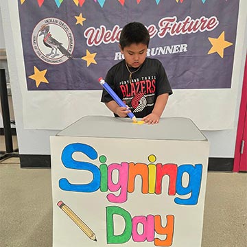 Boy signing a paper to be a future student Boy signing a paper to be a future student