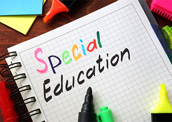 the words special education in a notebook surrounded by colored markers