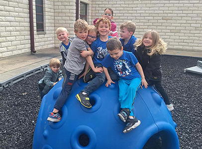 Group of children sitting on a piece of playground equipment