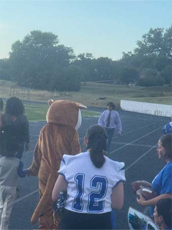 Mascot and students walking on a track