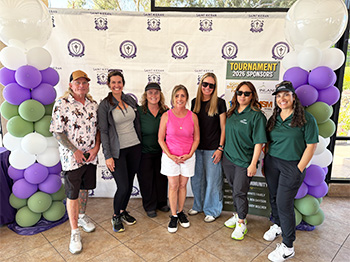 Group of adults posing for a picture under 2026 Tournament banner
