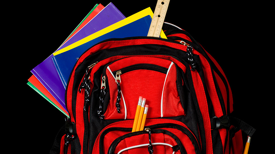 A red school backpack stuffed full of school supplies