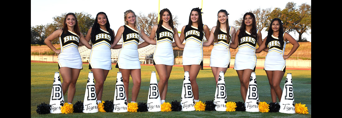 Girls cheerleading team posing for a picture on the football field