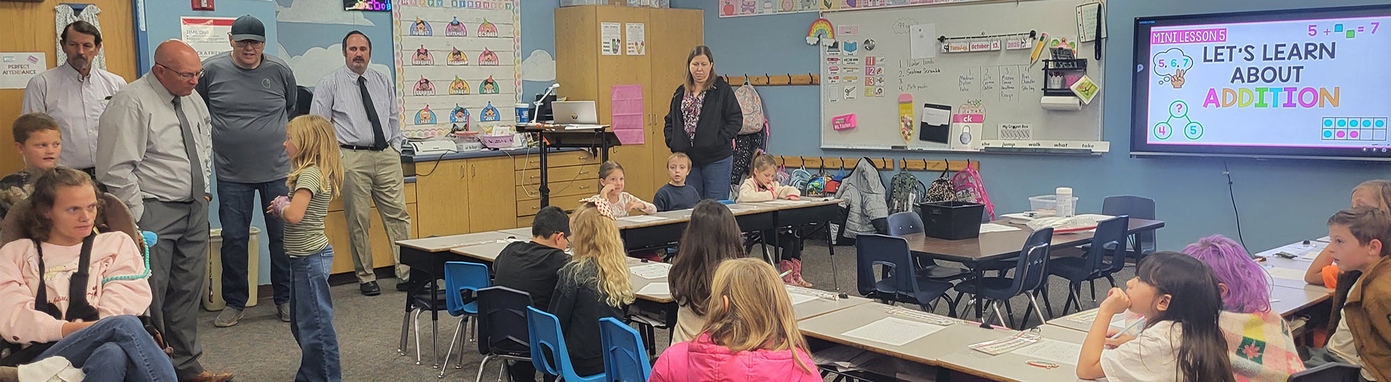 Governing board attending a classroom and helping with a lesson about addition