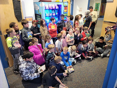 Group of students sitting on the floor in front of the new book machine