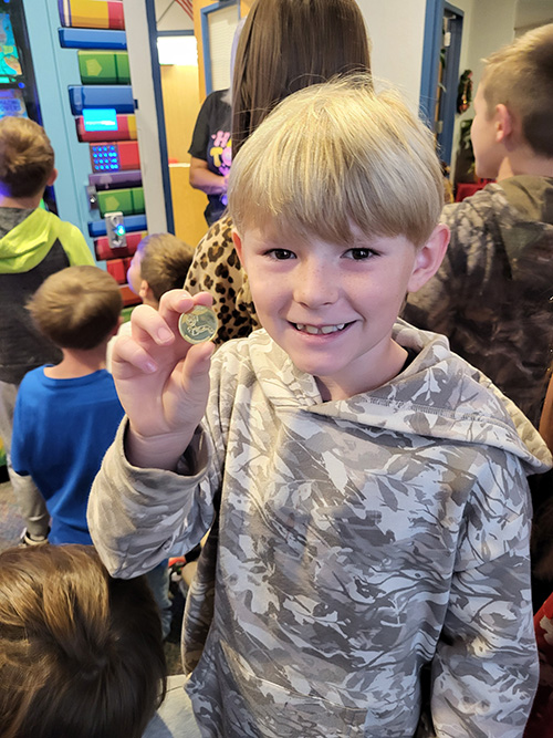 Happy student holding up a coin
