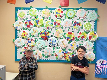 Two middle school students in front of an art display