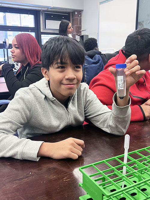 Student at LESP holding up a test tube during a BioBus science experience