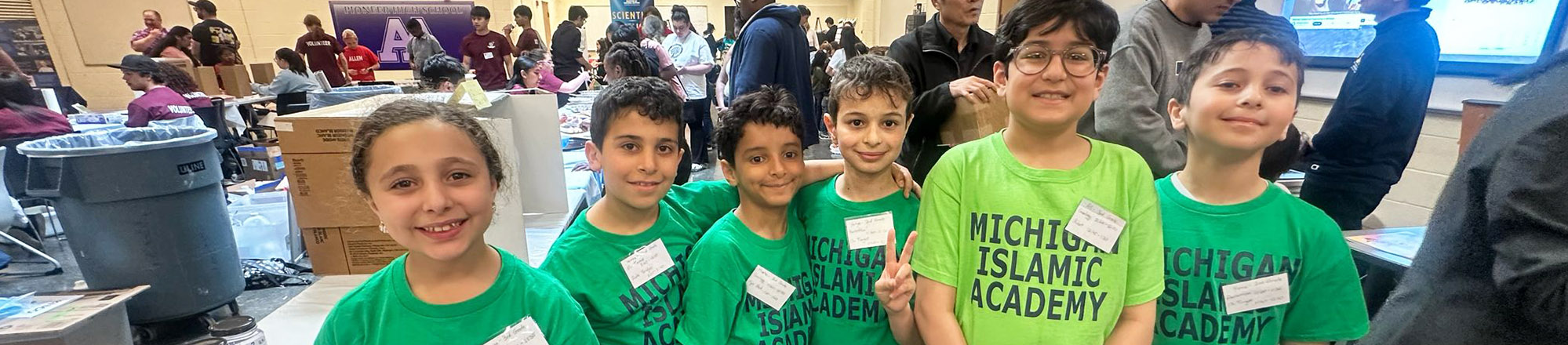 Group of happy students in green school t-shirts posing for a picture