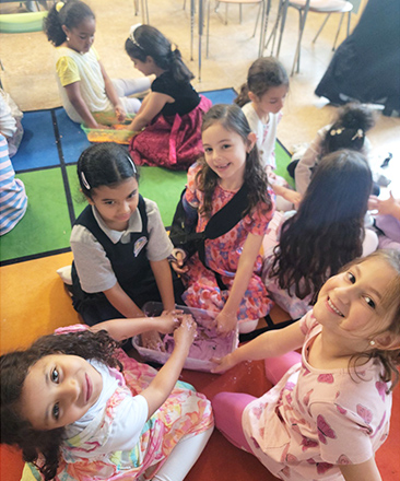 Happy first grade students sitting in circle on the classroom floor