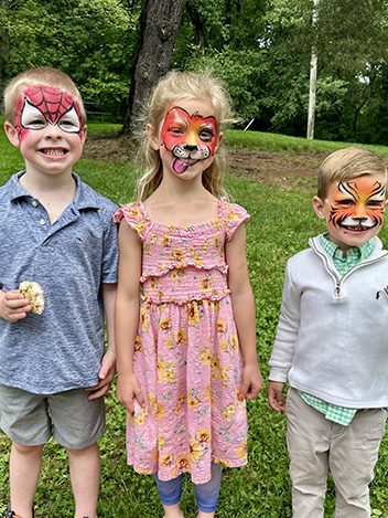 Three happy students with faces painted outside