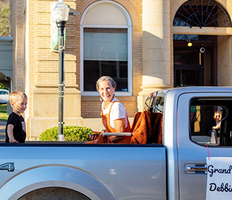Woman smiling from a truck with a young student