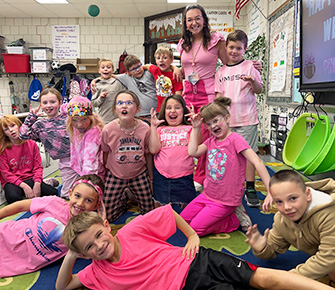 Happy teacher with students dressed in pink t-shirts