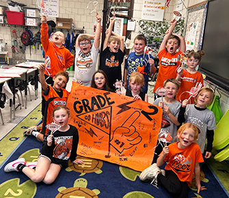 Second grade students holding up a banner