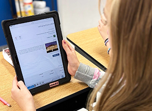 Student at her desk reading on her tablet computer