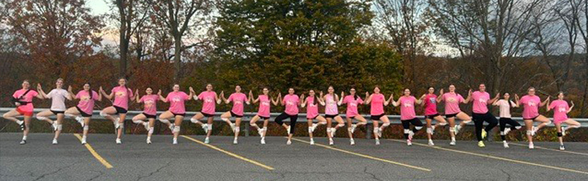 Students in pink shirts lined up outside and putting hands together