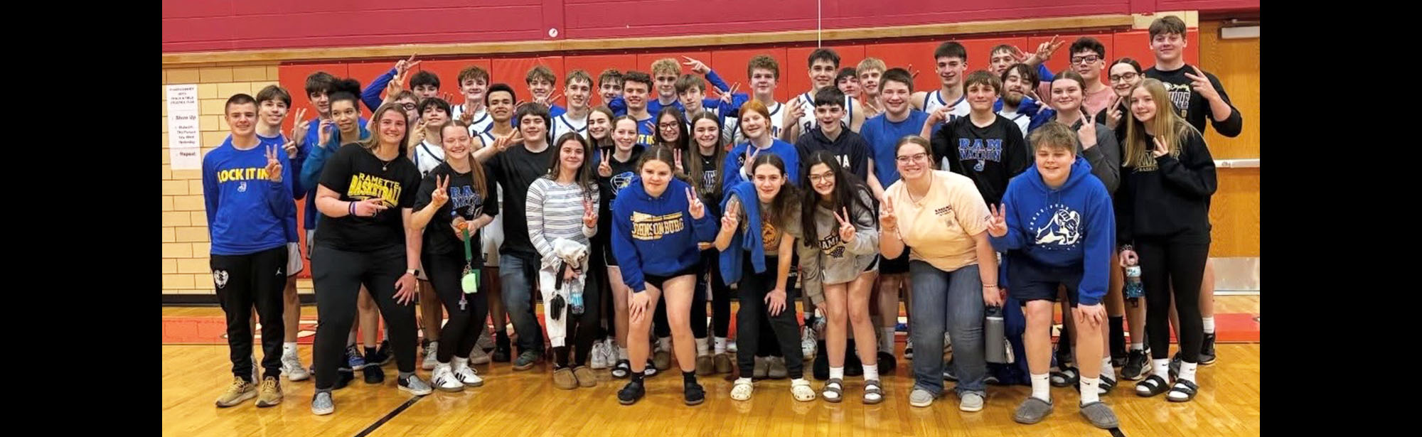 Group of happy students posing for a photo in the school gym