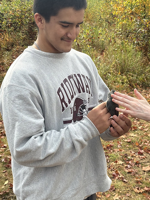 Student carefully holding a little bird during a field trip