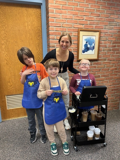 Happy woman with three helpful students in blue aprons next to a coffee cart