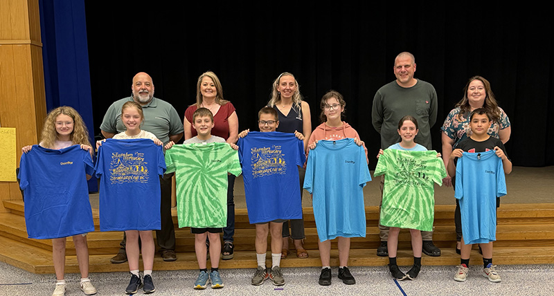 Representatives from Domtar presenting 6th grade students with blue and green T-shirts for their Washington DC trip