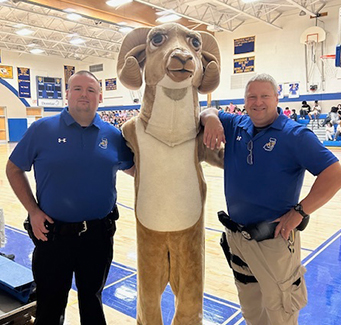 Two school admins taking a picture with the school masco