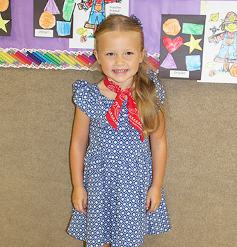 Elementary school girls in a blue dress with red scarf