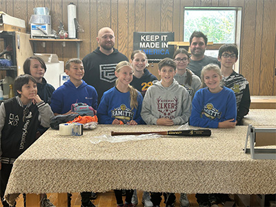 students and adults at a table with a baseball bat on it