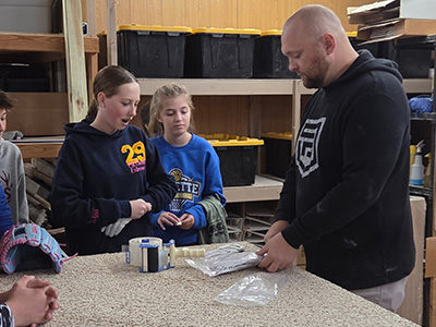 students watching an adult work on a project