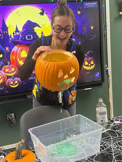 Teacher holding a carved pumpkin